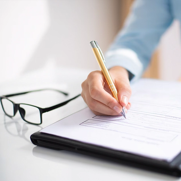 A hand fills out a form, representing the services offered by top immigration consultants in Kochi